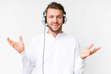 Tele pazarlamacı, beyaz bir arka planda, şok olmuş bir yüz ifadesiyle çalışan beyaz kulaklıklı beyaz bir adam.