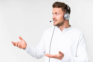 Tele pazarlamacı beyaz kulaklıkla çalışan beyaz bir adam. Şaşırtıcı bir yüz ifadesi var.