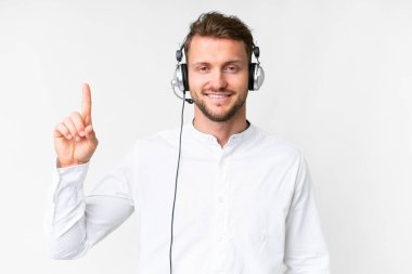 Tele pazarlamacı, beyaz arka planda kulaklıkla çalışan beyaz bir adam en iyinin işaretini veriyor ve parmağını kaldırıyor.
