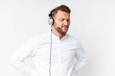 Tele pazarlamacı, beyaz arka planda kulaklıkla çalışan beyaz bir adam gayret gösterdiği için sırt ağrısı çekiyor.