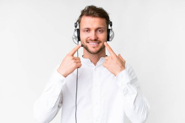 Tele pazarlamacı beyaz kulaklıkla çalışan beyaz bir adam mutlu ve hoş bir ifadeyle gülümsüyor.