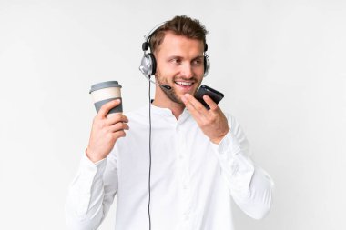 Kafkasyalı tele pazarlamacı, izole edilmiş beyaz arka planda çalışan elinde kahve ve cep telefonu olan bir adam.
