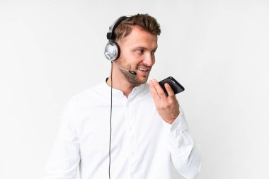 Tele pazarlamacı beyaz arka planda kulaklıkla çalışan beyaz bir adam cep telefonuyla sohbet ediyor.