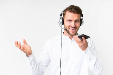 Tele pazarlamacı beyaz arka planda kulaklıkla çalışan beyaz bir adam cep telefonuyla sohbet ediyor.