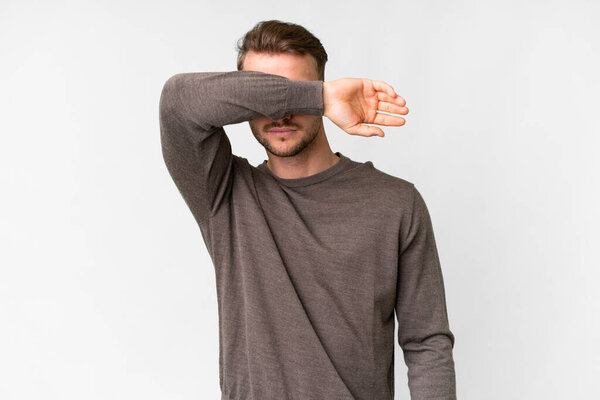 Young handsome caucasian man over isolated white background covering eyes by hands