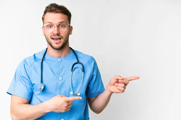 Junge Krankenschwester Mann Über Isolierten Weißen Hintergrund Überrascht Und Zeigt — Stockfoto