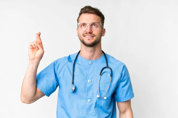 Jovem Enfermeira Homem Sobre Isolado Fundo Branco Com Dedos Cruzando — Fotografia de Stock