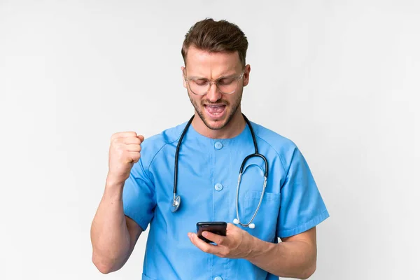 Ung Sjuksköterska Man Över Isolerad Vit Bakgrund Med Telefon Seger — Stockfoto