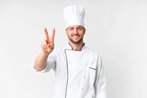 Jonge Kaukasische Chef Kok Geïsoleerde Witte Achtergrond Glimlachen Tonen Overwinning — Stockfoto