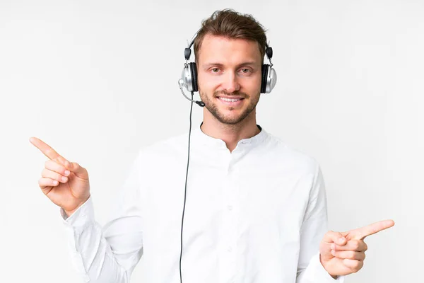 Stock image Telemarketer caucasian man working with a headset over isolated white background pointing finger to the laterals and happy