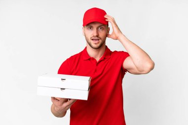 İş üniformalı bir pizzacı, izole edilmiş beyaz arka planda pizza kutuları alıyor. Sürpriz bir ifadeyle.