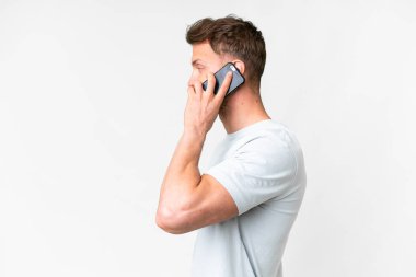 İzole edilmiş beyaz bir geçmişi olan yakışıklı beyaz bir adam cep telefonuyla sohbet ediyor.