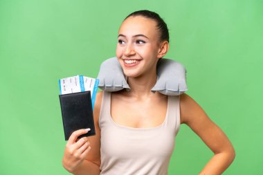 Şişirilebilir Seyahat Yastığı 'na sahip genç bir Arap kadın soyutlanmış arka planda kolları kalçasında ve gülümsüyor.