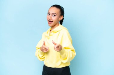 Genç bir Arap kadın, mavi arka planda izole edilmiş ve gülümsüyor.