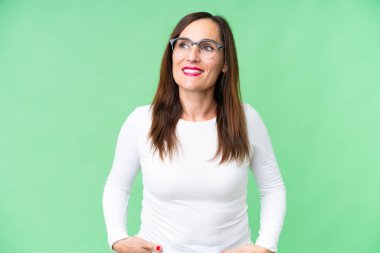 Middle age woman over isolated chroma key background thinking an idea while looking up