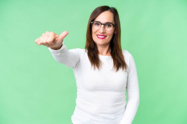 Orta yaşlı bir kadın izole edilmiş krom anahtar geçmişi var. Baş parmak işareti yapıyor.