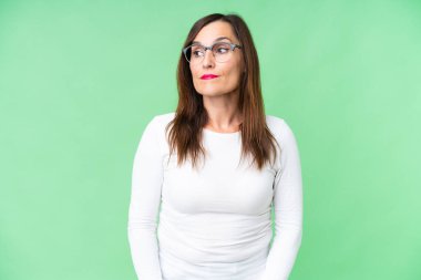 Orta yaşlı kadın izole edilmiş krom anahtar arka planda şüpheli hareketler yapıyor.