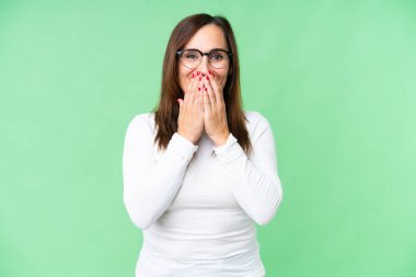 Orta yaşlı kadın izole edilmiş krom anahtar arka planda mutlu ve gülümseyen elleri ile ağzını kapatıyor.