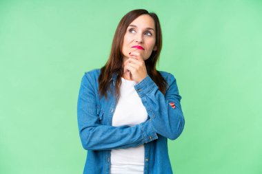 Orta yaşlı kadın izole edilmiş krom anahtar arka planda kuşkuları ve kafa karıştırıcı yüz ifadesi olan