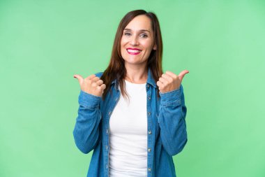 Middle age woman over isolated chroma key background with thumbs up gesture and smiling