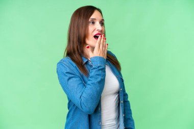 Orta yaşlı kadın izole edilmiş krom anahtar arka planda esniyor ve geniş bir ağzı eliyle kapatıyor.