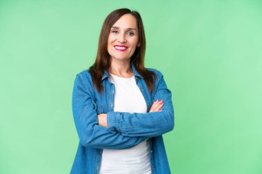 Middle age woman over isolated chroma key background with arms crossed and looking forward