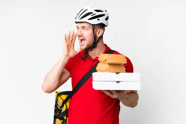 stock image Young delivery man taking a takeaway food over isolated white background shouting with mouth wide open to the side