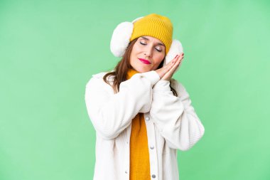 Orta yaşlı bir kadın, izole edilmiş krom anahtar arka plan üzerine kış maskesi takıyor. Uyku jesti yapıyor.