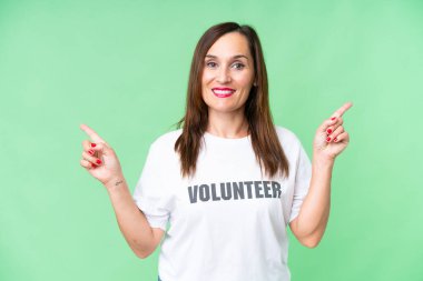 Orta yaşlı gönüllü kadın izole edilmiş krom anahtar geçmişi var. Parmak uçlarını işaret ediyor ve mutlu.