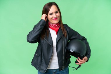 Motorsiklet kasklı orta yaşlı beyaz kadın izole edilmiş krom anahtar arka planda hayal kırıklığına uğramış ve kulaklarını kapatmış.