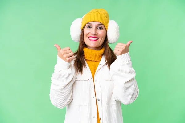 中年妇女戴着冬衣 戴在孤立的彩色关键背景上 竖起大拇指 微笑着 — 图库照片