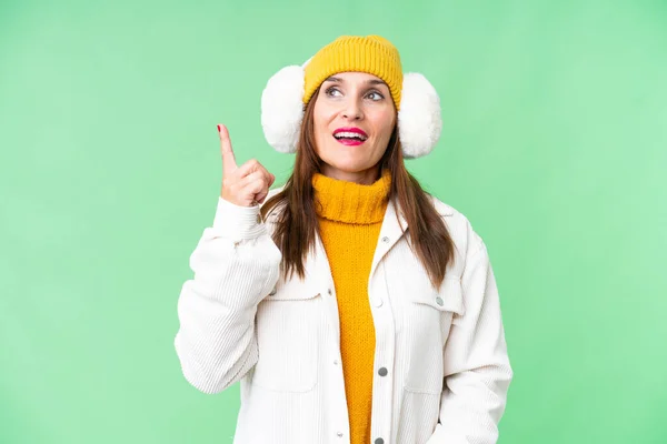 中年妇女带着冬衣罩在孤立的彩色关键背景上 想在举起一只手指头的同时实现这个解决方案 — 图库照片