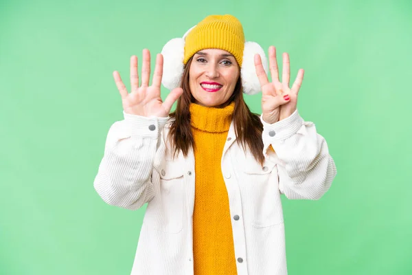 中年妇女戴着冬衣在孤立的彩色关键背景上 用手指数着9 — 图库照片