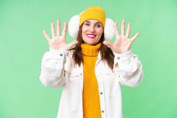 中年妇女戴着冬衣 戴在孤立的彩色关键背景上 用手指数着10 — 图库照片