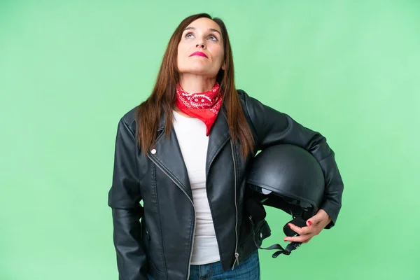 中年Caucasian女性とともにオートバイヘルメット上の隔離されたクロマキー背景と見上げます — ストック写真