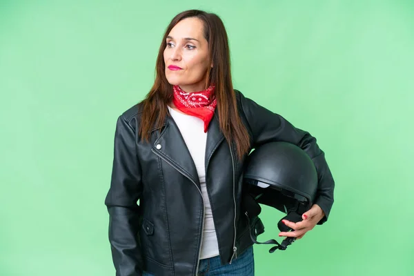 中年Caucasian女性とともにオートバイヘルメット以上隔離されたクロマキー背景見ますザ側 — ストック写真