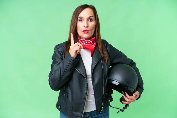 中年Caucasian女性とともにオートバイヘルメット上の隔離されたクロマキー背景を実現しようとして解決策を持ち上げながら指アップ — ストック写真