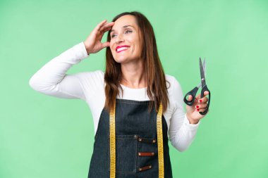 Seamstress woman over isolated chroma key background smiling a lot