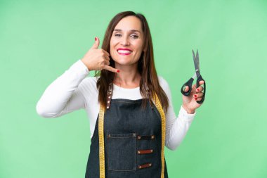 Seamstress woman over isolated chroma key background making phone gesture. Call me back sign