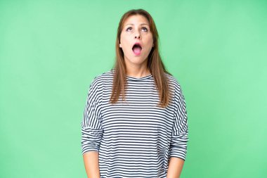 Orta yaşlı bir kadın soyutlanmış bir şekilde yukarı bakıyor ve şaşırmış bir ifadeyle