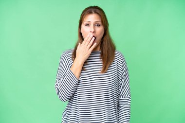 Middle age woman over isolated background yawning and covering wide open mouth with hand