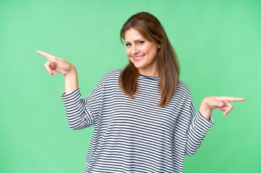 Middle age woman over isolated background pointing finger to the laterals and happy