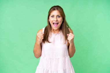 Middle age woman over isolated background celebrating a victory in winner position