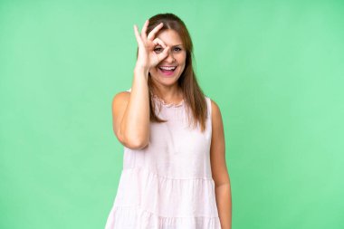 Middle age woman over isolated background showing ok sign with fingers