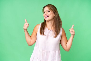 Middle age woman over isolated background giving a thumbs up gesture