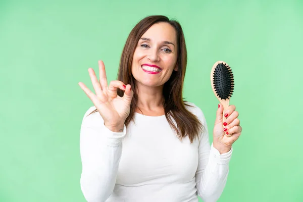Middle age woman with hair comb over isolated chroma key background showing ok sign with fingers
