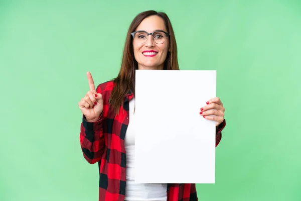 中年妇女拿着一个空标语牌 举着一个空标语牌 站在孤立的彩色背景上 — 图库照片