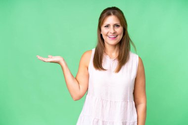 Arka planda izole edilmiş orta yaşlı bir kadın bir ilan vermek için avucunun içinde hayali bir alan tutuyor.