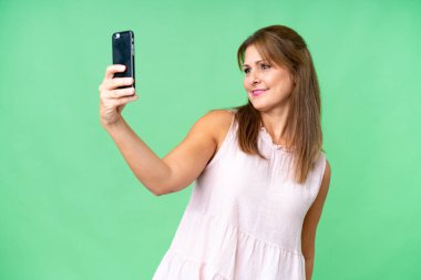 Tecrit edilmiş orta yaşlı bir kadın selfie çekiyor.