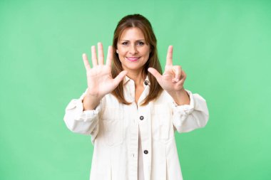 Soyutlanmış arka planda orta yaşlı bir kadın parmaklarıyla yediyi sayıyor